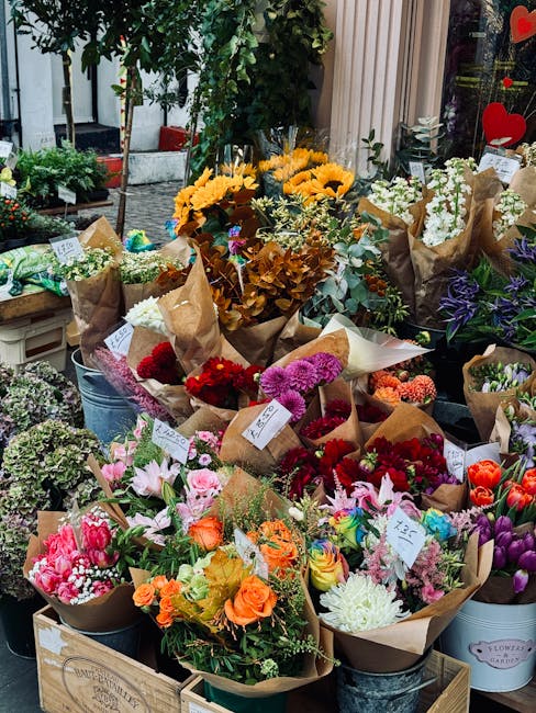 A vibrant display of freshly arranged flower bouquets on a flower shop window ledge, showcasing a variety of blooms including sunflowers, pink lilies, red gerberas, purple irises, and white roses, eac